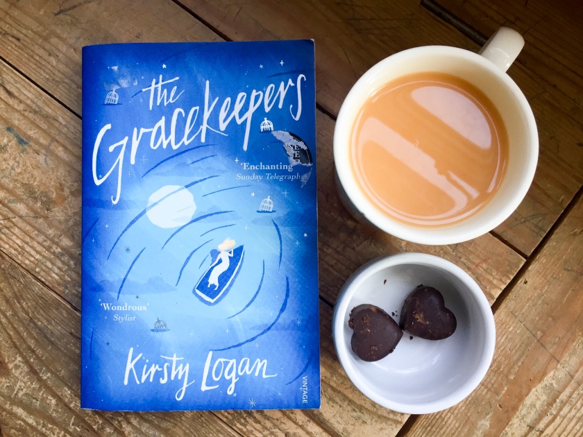 The Gracekeepers, a novel by Kirsty Logan, two heart-shaped truffles, and a cup of rooibos tea with almond milk.
